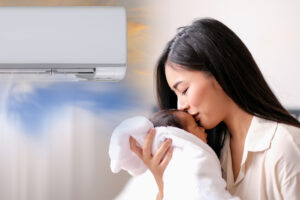 A woman kisses a baby wrapped in a towel near an air conditioner.