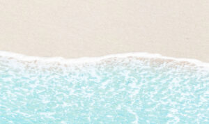 Aerial view of gentle ocean waves lapping against a sandy beach.