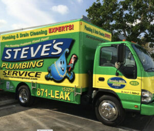 A brightly colored plumbing service truck with text advertising "Steve's Plumbing Service" and contact number 871-LEAK. The truck is parked on a sunny day next to a tree.